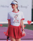 Person wearing a Betty Boop-themed shirt and visor on a tennis court