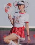 Person wearing a Betty Boop-themed shirt and visor on a tennis court