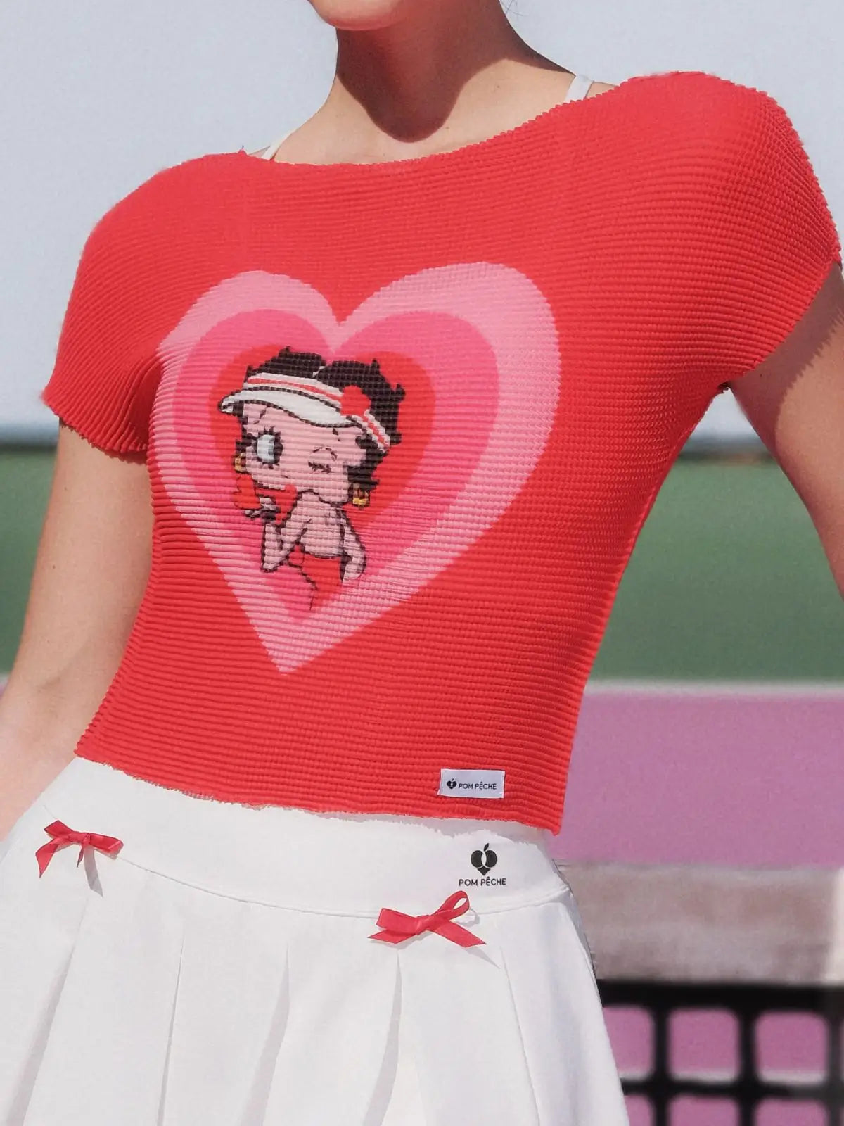 Red knit top with cartoon character in a heart design worn by a person.