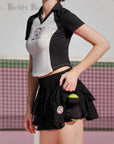 Person wearing a black and white sports outfit with a logo on a tennis court.