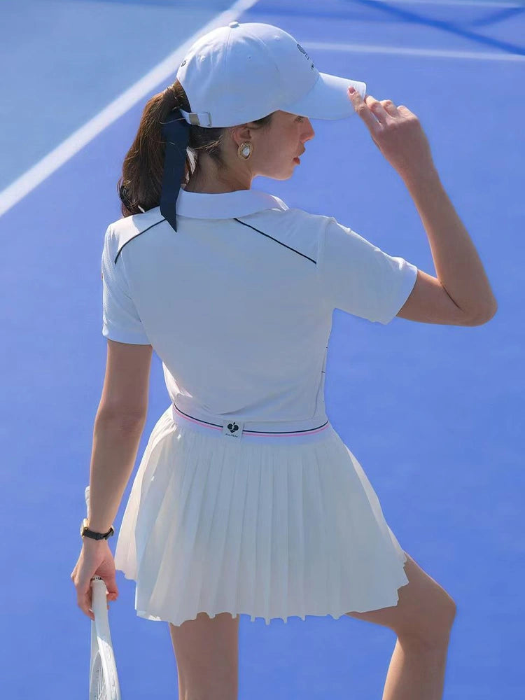 Person in a white tennis outfit on a blue tennis court