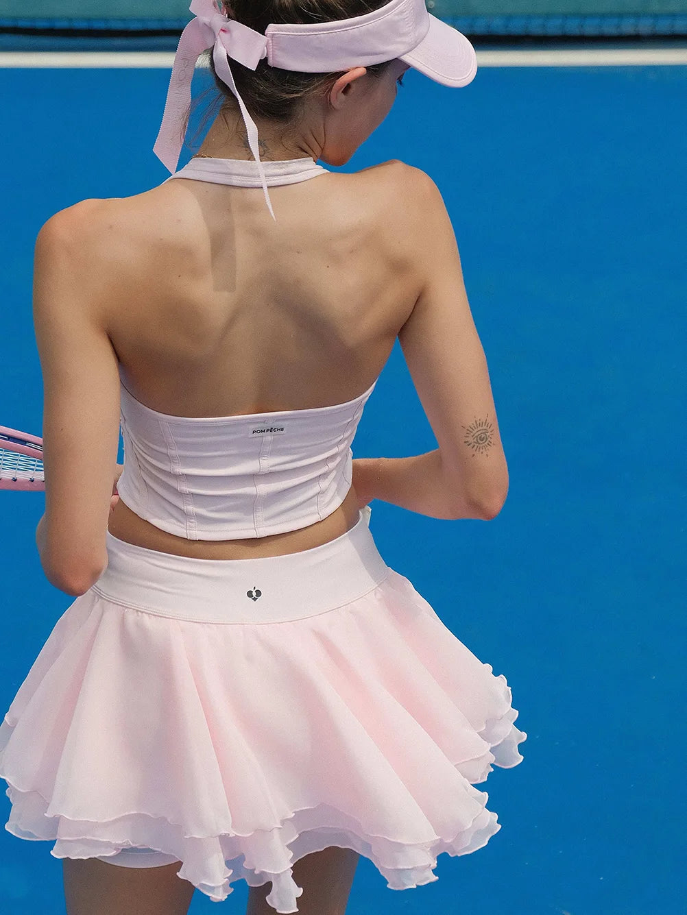 Person wearing a white tennis outfit with a visor against a blue background