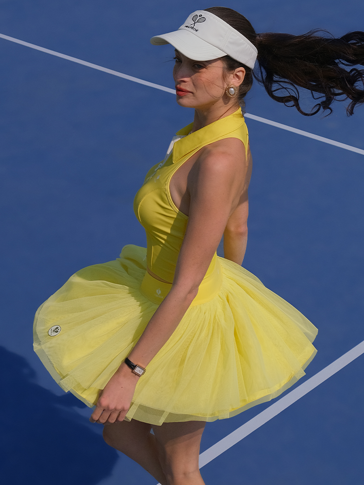Yellow puff tulle tennis skirt styled with halter athletic top, highlighting floating mesh layers and high-waisted tennis skirt movement.