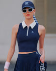 Short pleated tennis skirt in navy blue, front view featuring asymmetrical hemline and classic knife pleats.