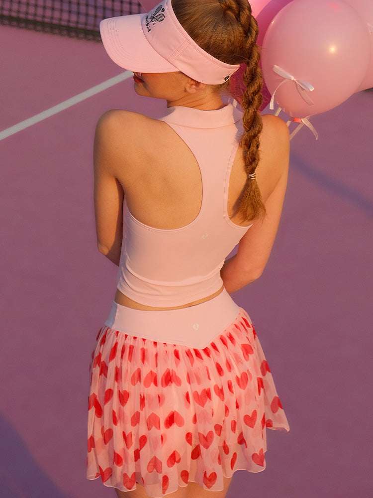 Light pink zip-front tennis tank with a collar and subtle logo, offering a chic look for on-court wear.