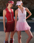 Two women in red and pink tennis outfits standing outdoors.