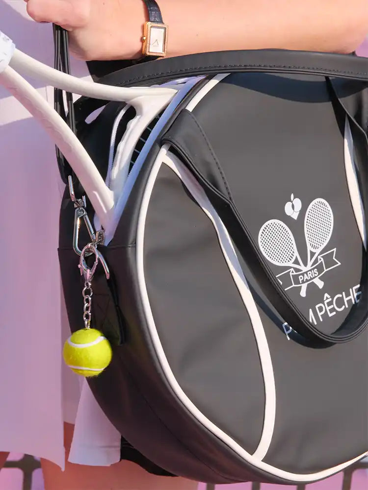 Tennis racket and ball with a branded bag on a pink background
