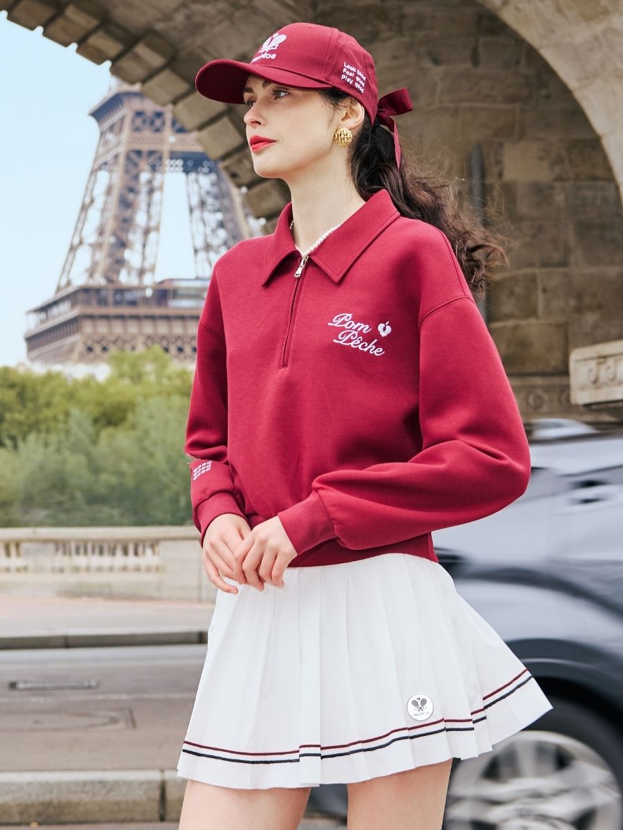 Red sweatshirt with quarter-zip design and embroidered logo on the front and back, offering a stylish and sporty look.