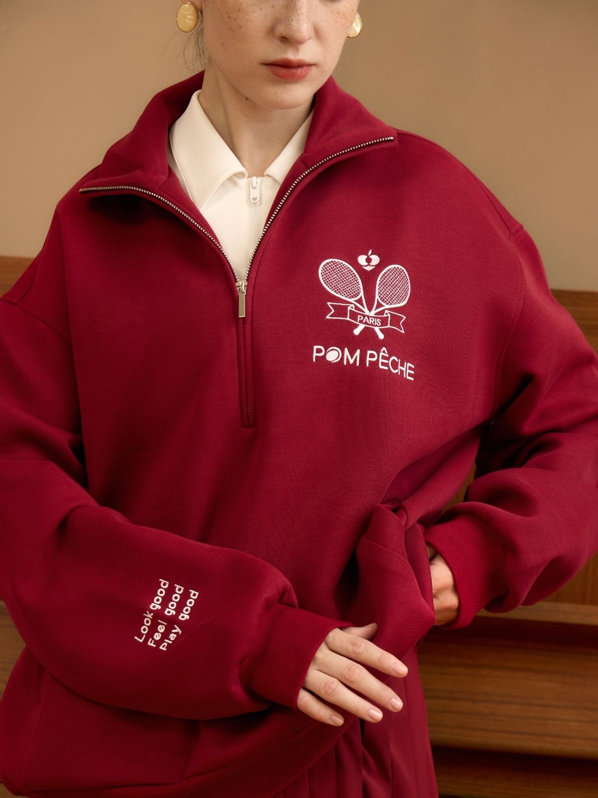 Person wearing a red fleece pullover with 'Pom Peche' branding.