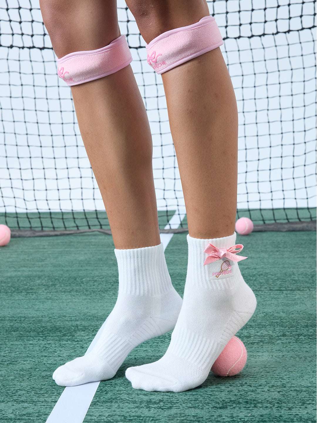 White ankle tennis socks with red bow detail and Pom Pêche logo, styled on the court.
