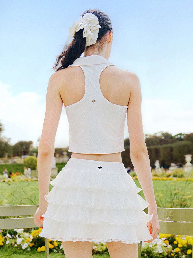 White cropped tennis top with ruffled collar and sleeveless design, featuring a subtle logo for a chic, sporty look.