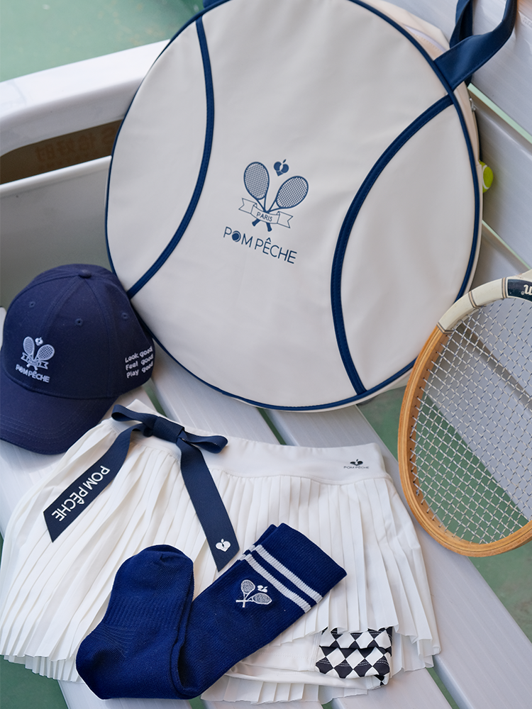 White round tennis bag with blue trim and handles, featuring Pom Pêche logo.