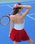 Wine red puff tulle tennis skirt styled with white halter top, highlighting floating mesh layers and high-waisted tennis skirt silhouette.
