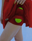 Close-up of wine red tulle puff tennis skirt with built-in shorts, showing tennis ball pocket and high-waisted athletic tennis skirt detail.
