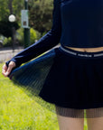 Spin Layered Mesh Pleated Tennis Skirt Navy close-up, showcasing lightweight layered pleated mesh, airy flowy skirt detail, and elegant tennis skort design
