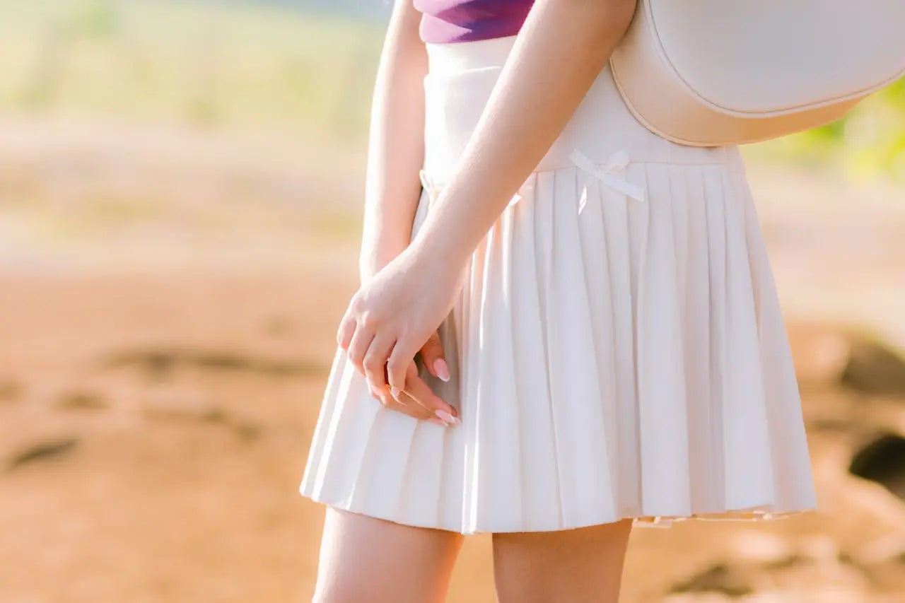 Woman wearing white pelated skirt. 