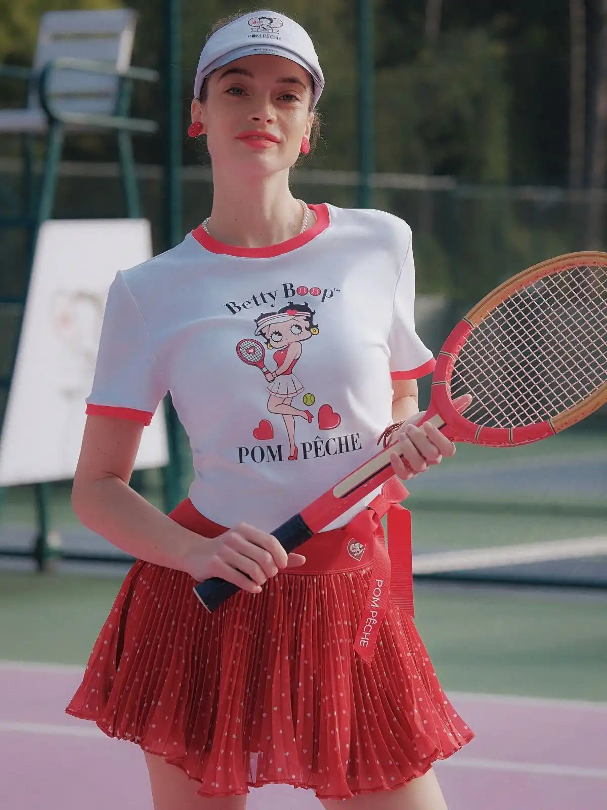 Person wearing a Betty Boop-themed shirt and visor on a tennis court