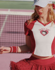 Person wearing a red and white outfit with a heart design on a tennis court