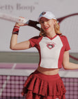Person in a red and white outfit with a cap, holding a tennis racket on a tennis court.