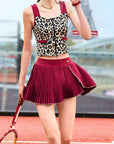 Person wearing a leopard print top and red skirt on a tennis court