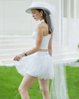 Side view of white puff tulle tennis skirt styled with sporty top, showing airy layered mesh and high-waisted athletic skirt silhouette.