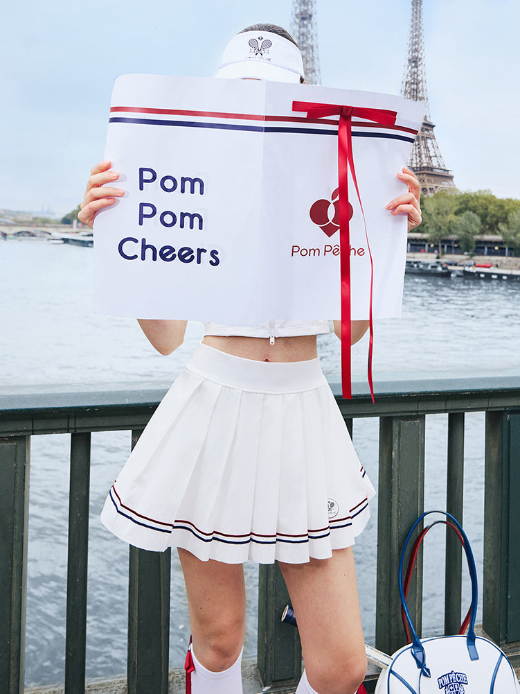 Person holding a 'Pom Pom Cheers' sign with the Eiffel Tower in the background
