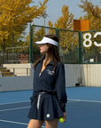 Woman wearing a navy blue sports outfit with a white headband on a light gray background
