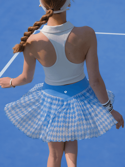 Back view of the Argyle Mesh Tennis Skirt in Blue flaring out during movement on a tennis court, emphasizing its flowy mesh construction.