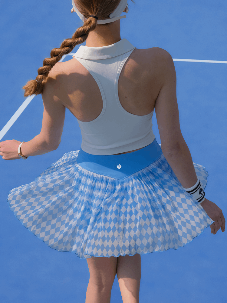 Back view of the Argyle Mesh Tennis Skirt in Blue flaring out during movement on a tennis court, emphasizing its flowy mesh construction.