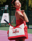Woman in a red dress with a Betty Boop bag on a tennis court