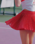 Person wearing a red polka dot skirt on a tennis court