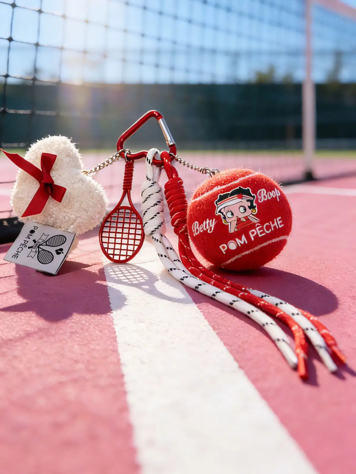 Tennis-themed keychain with a heart-shaped item on a tennis court