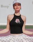 Black halter top with graphic design worn by a person, with a blurred background.