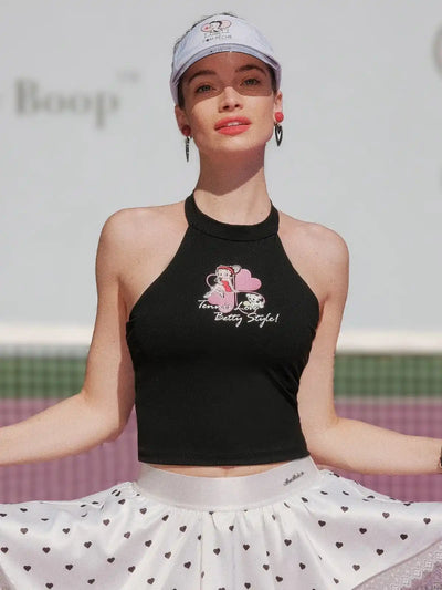 Black halter top with graphic design worn by a person, with a blurred background.