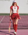 Woman in red and white tennis outfit with a racket on a tennis court