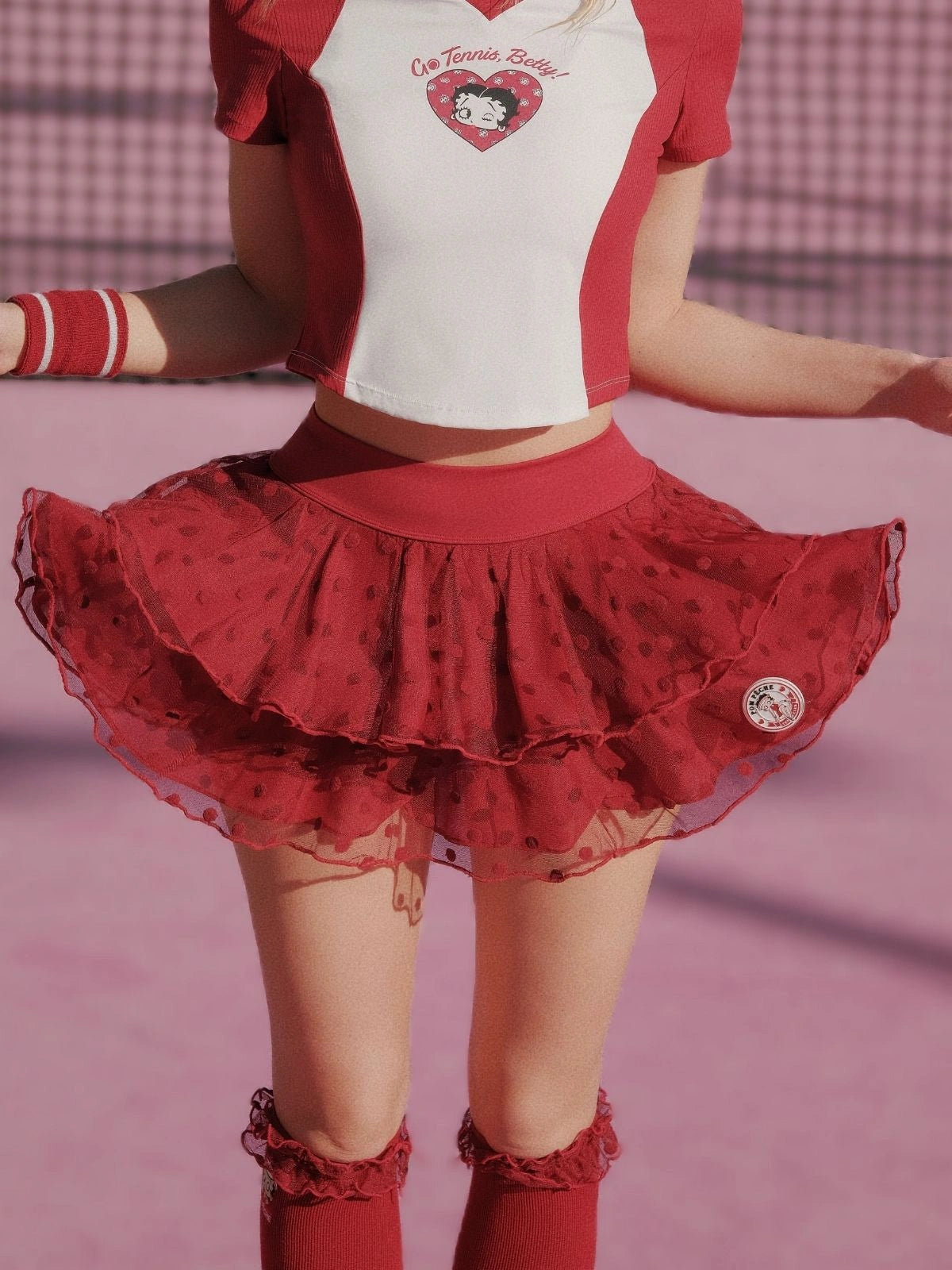 Person wearing a red and white outfit with a heart design on a pink background