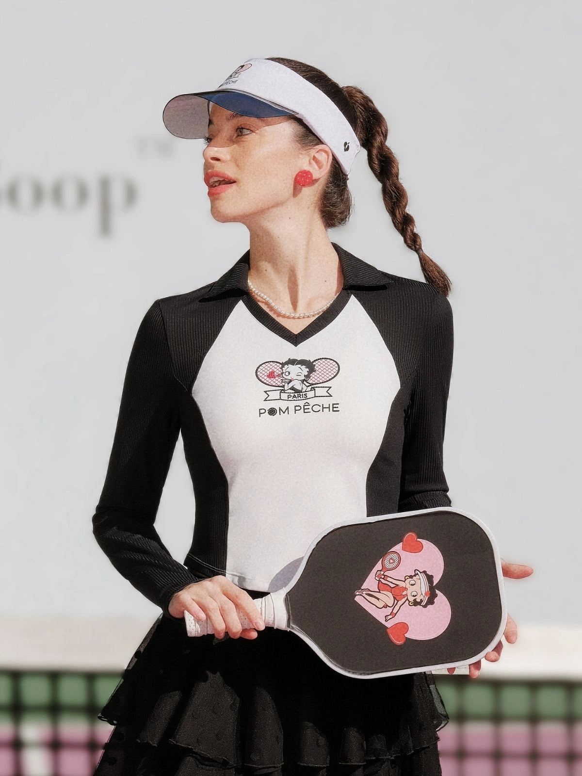 Woman holding a pickleball paddle with a visible brand logo on a court.
