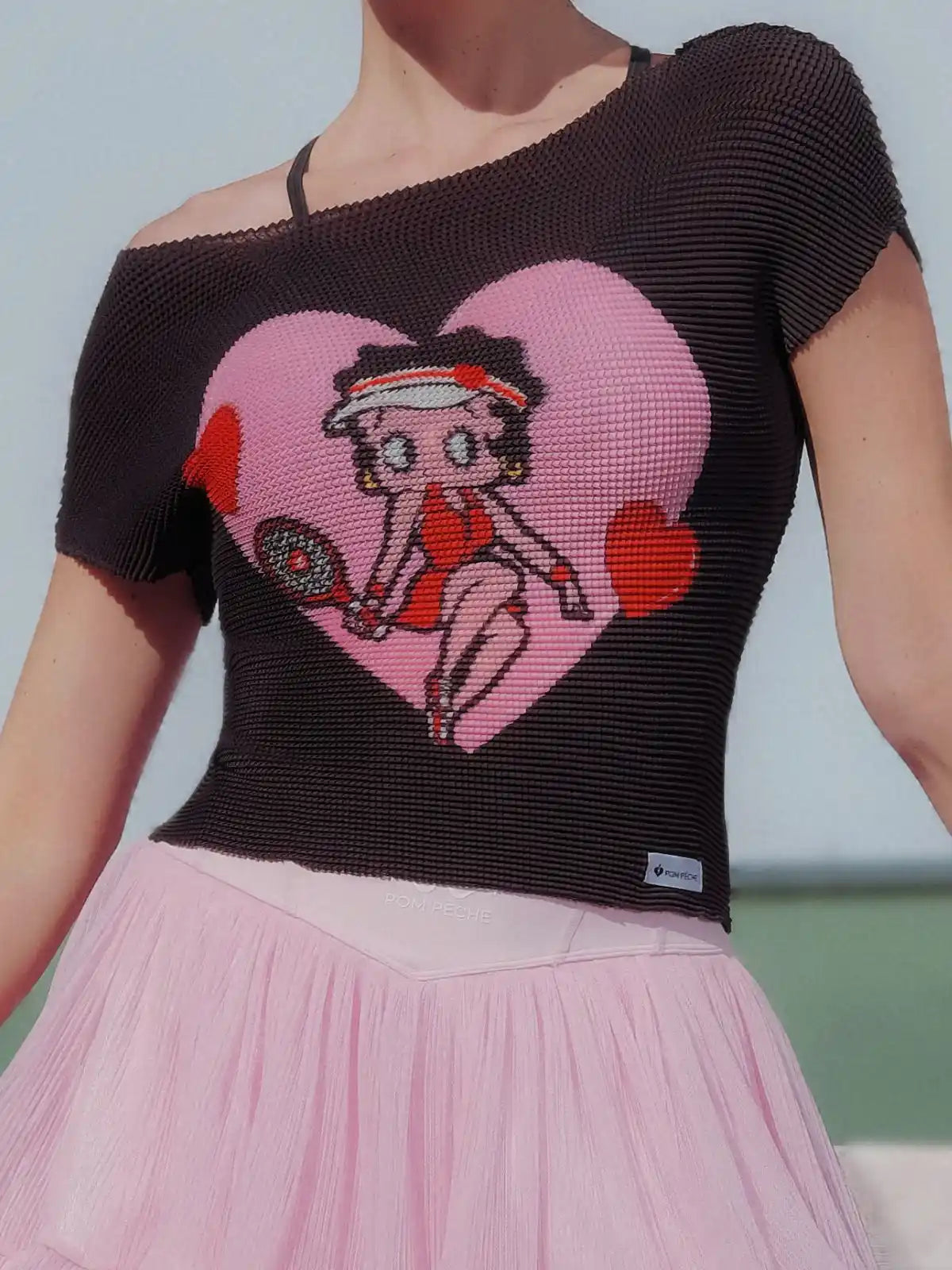 Person wearing a black knit top with a cartoon character design on a pink heart.