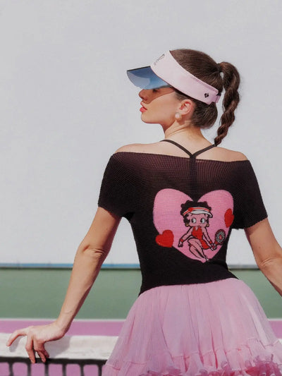 Woman wearing a black top with a cartoon character design and a pink tutu skirt.