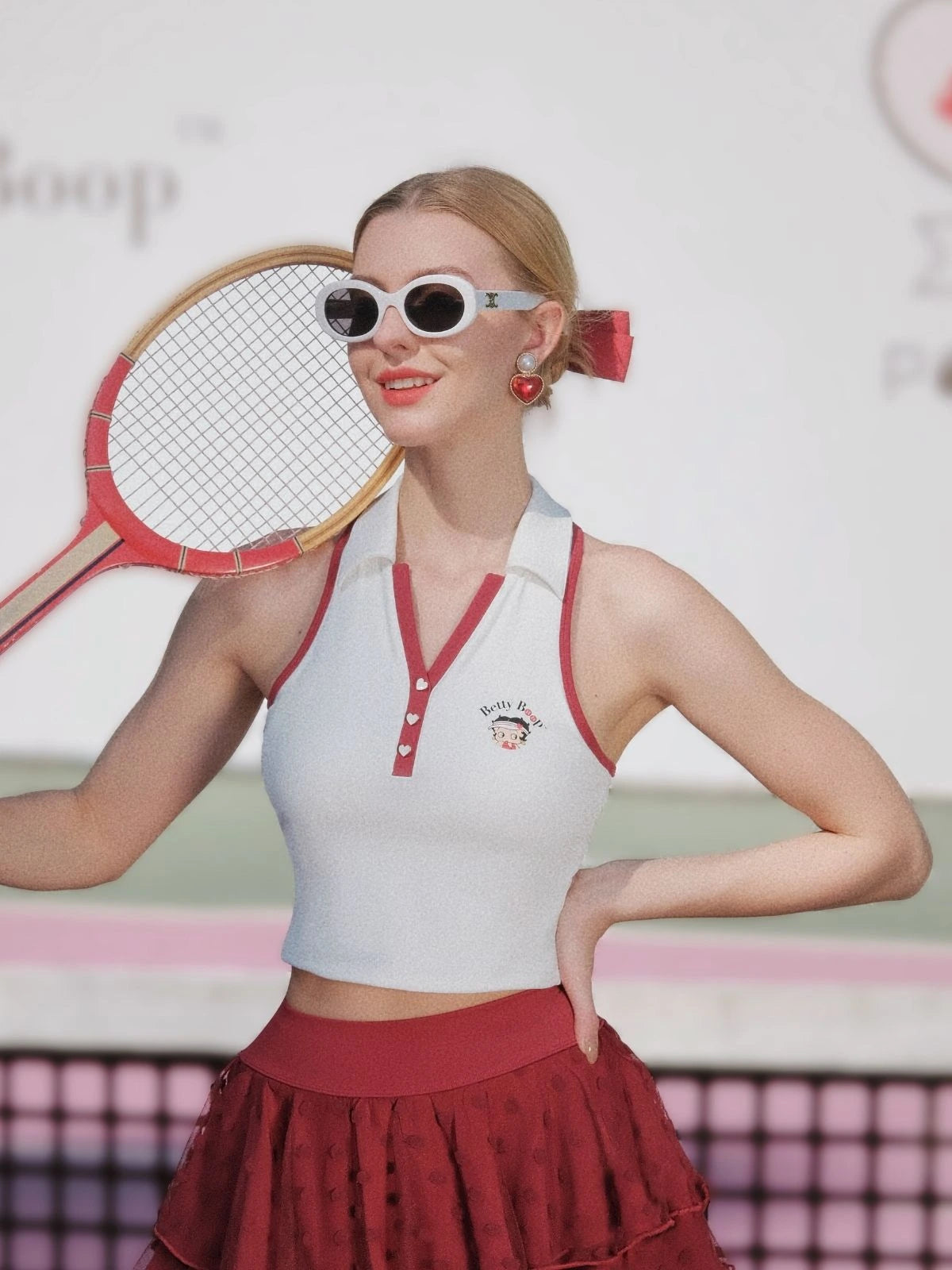 Woman in vintage tennis outfit holding a racket on a tennis court
