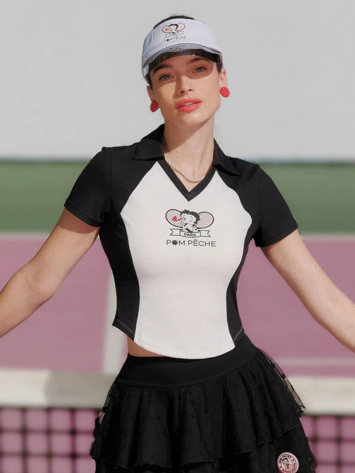 Woman wearing a black and white polo shirt with a logo on a sports court