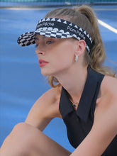 Black checkered tennis visor with Pom Pêche logo and adjustable strap.