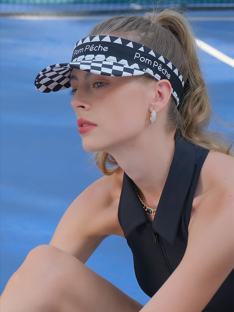 Black checkered tennis visor with Pom Pêche logo and adjustable strap.