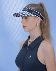 Black checkered tennis visor with Pom Pêche logo and adjustable strap.