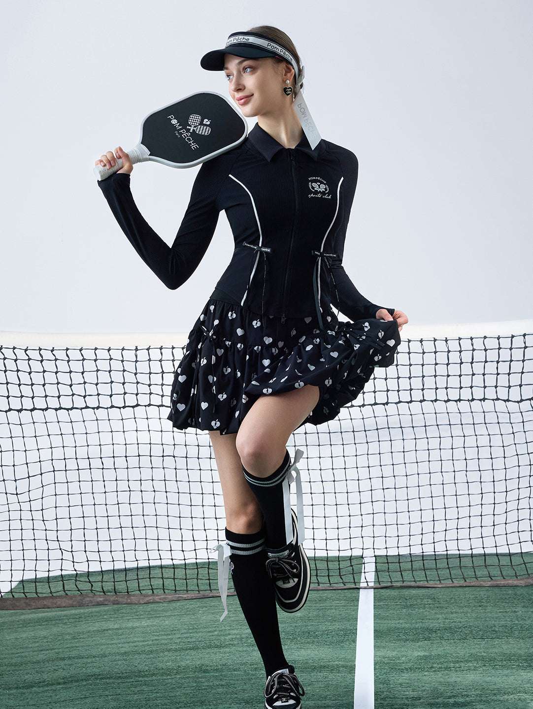 Black sun-protective tennis jacket with a sculpted fit, adjustable waist ties, and dual ball pockets.