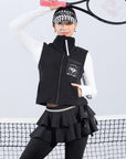 Warm black fleece vest with high-neck zip design and embroidered chest pocket, styled on the tennis court.