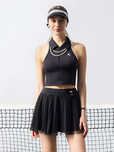 Black pleated tennis skirt with soft mesh lace and subtle heart details, offering a lightweight feel, styled on a tennis court. 
