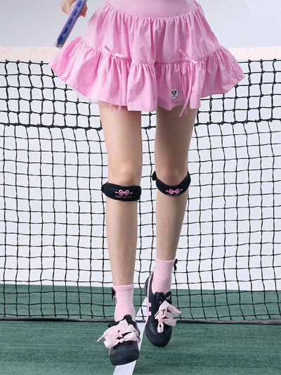 Tennis look featuring a black patella support strap with bow print. 