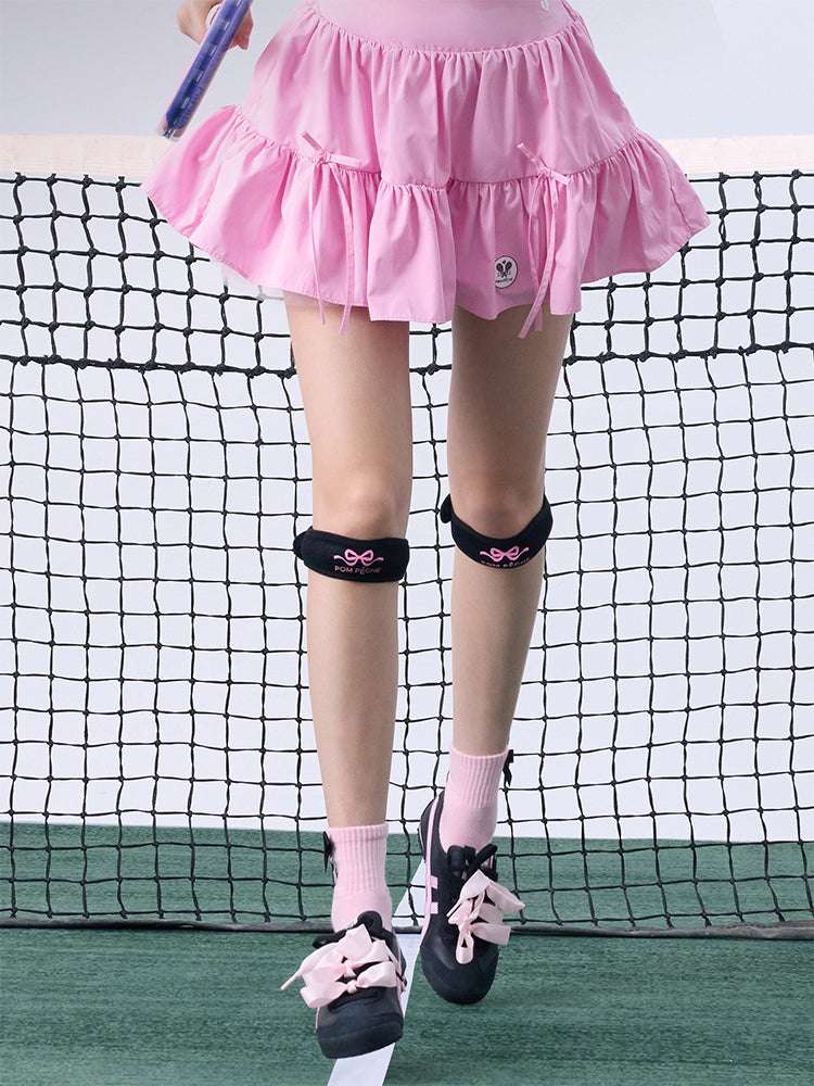 Tennis look featuring a black patella support strap with bow print. 