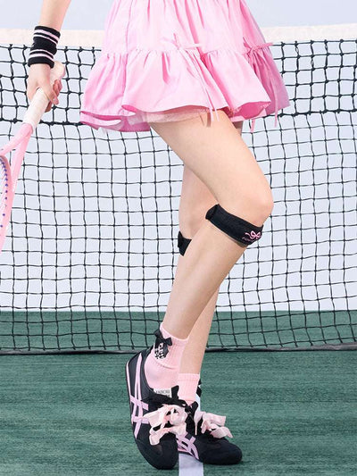 Tennis look featuring a black patella support strap with bow print. 